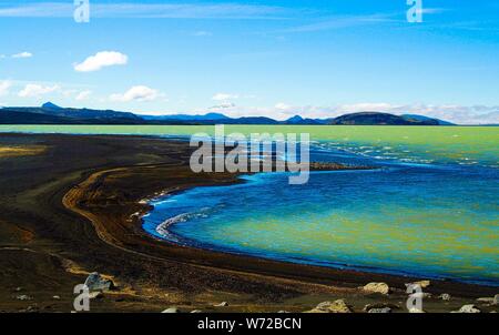 Blick über schwarzen vulkanischen Sand Strand auf remote isoliert blau und grün schimmernde Wasser gegen den blauen Himmel - Kleifarvatn See Island Stockfoto