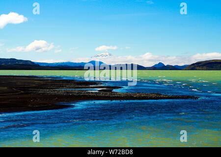 Blick über schwarzen vulkanischen Sand Strand auf remote isoliert blau und grün schimmernde Wasser gegen den blauen Himmel - Kleifarvatn See Island Stockfoto