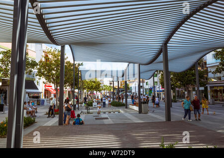 Torremolinos, Provinz Malaga, Andalusien, Spanien - Juni 19., 2019: Menschen laufen unter Sonnenschirmen an der Costa del Sol entfernt im Zentrum von Torre Stockfoto