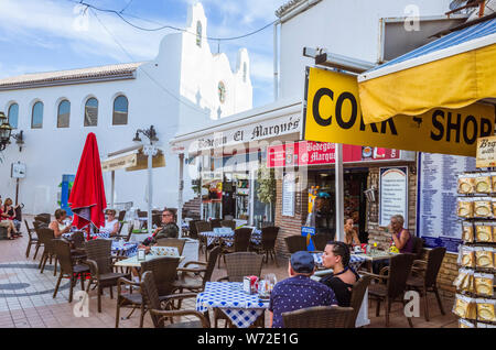 Torremolinos, Provinz Malaga, Andalusien, Spanien - Juni 19., 2019: die Menschen sitzen in einem Cafe im Freien durch die Kirche von San Miguel im Zentrum von Torrem Stockfoto