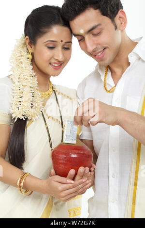 Südindische Frau, eine Münze in ein Sparschwein mit ihrem Ehemann Stockfoto