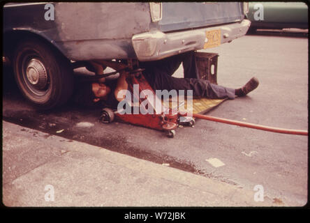 Mann bei der Arbeit AUF DEM AUTO IN HELL'S KITCHEN, NEW YORK CITY. Die innere Stadt IST HEUTE EIN ABSOLUTER WIDERSPRUCH ZU DEN MAIN STREAM AMERIKA VON TANKSTELLEN, Autobahnen, EINKAUFSZENTREN UND LOTS HÄUSER. Es ist bevölkert von Schwarzen, LATEINER UND DIE WEISSEN ARM. Vor allem die INNERSTÄDTISCHEN UMWELT IST DER MENSCH, SO SCHÖN UND BEDROHT, WIE DIE 19 Gebäude aus dem 17. Stockfoto