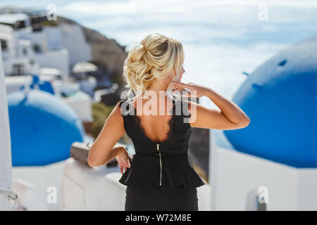 Schöne Frau in Kleid gegen das Meer und die Architektur der Insel Santorini, Griechenland Stockfoto