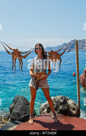 Junge Frau hält in den Händen von Hummer, auf dem Hintergrund des Meeres und der Oktopus auf einem Seil Stockfoto