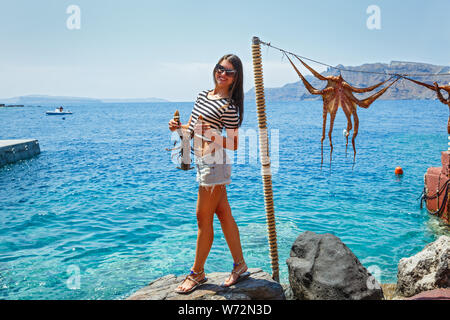 Junge Frau hält in den Händen von Hummer, auf dem Hintergrund des Meeres und der Oktopus auf einem Seil Stockfoto