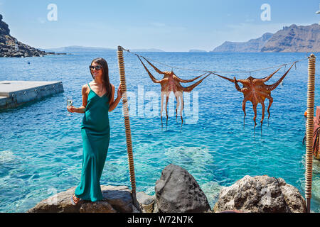 Junge Frau in Kleid auf dem Hintergrund des Meeres und ein Oktopus auf einem Seil Stockfoto