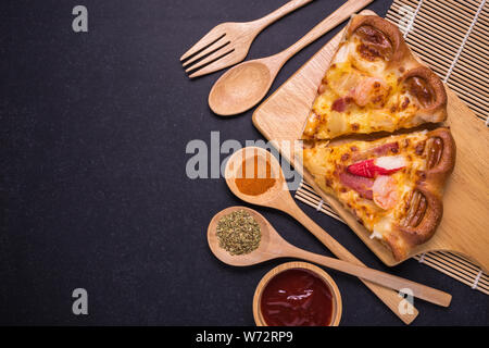 Ansicht von oben Stück Pizza auf der Holzplatte und schwarzer Stein Tabelle Hintergrund Stockfoto