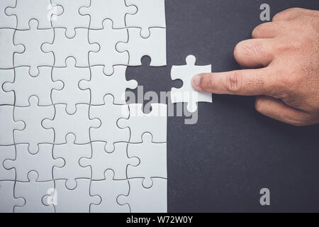 Verbindung Konzept: Hand, die Stücke von Jigsaw Puzzle und fügen Sie in die fehlende Bohrung Stockfoto
