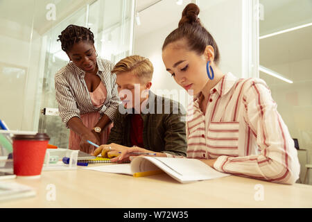 Konzentriert brunette Mädchen Aufgabe Lesen im Buch Stockfoto