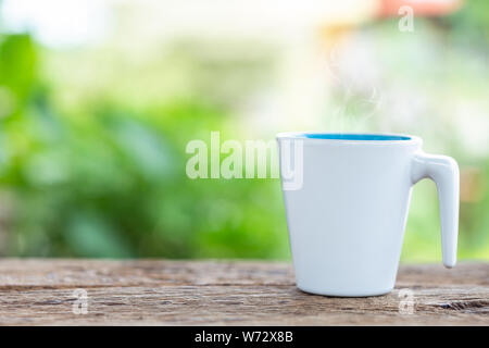 Close Up weiß Kaffeetasse auf hölzernen Tisch oder Theke im Coffee Shop und Unschärfe Licht bokeh Hintergrund Stockfoto
