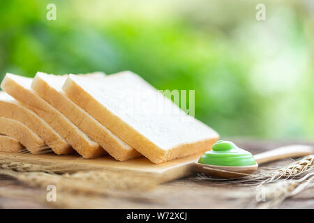 Schließen Sie zwei Brot auf hölzernen Tisch mit grünen Blur hellen Hintergrund. Essen Konzept Stockfoto
