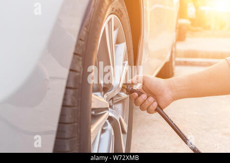 Mann, die Überprüfung des Luftdrucks und Füllung Luft in den Reifen seines Autos Stockfoto