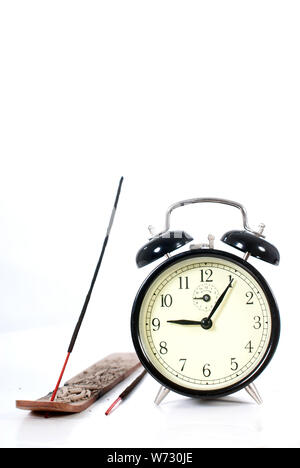 Räucherstäbchen für Entspannung und eine große Uhr neben. Konzeptionelle Idee, Zeit sich zu entspannen. Stockfoto