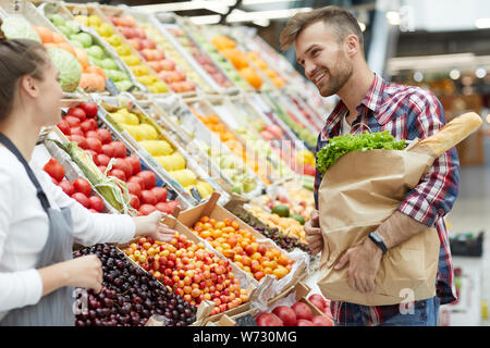 Seitenansicht Portrait von gutaussehenden jungen Mann sprechen zu Sales Assistent beim Einkaufen im Supermarkt, kopieren Raum Stockfoto