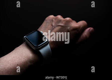 Tschechow, Russland - Juli 19, 2019: Apple Watch Serie 4 Farbe Weiß mit Hand. Eine neue Uhr aus der Firma Apple closeup auf dunklem Hintergrund isoliert Stockfoto