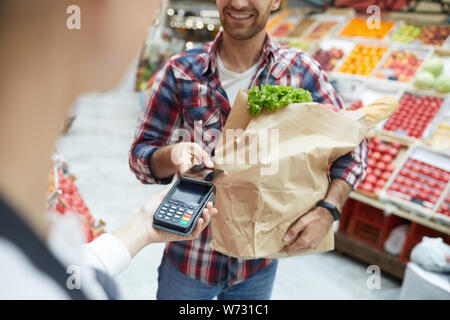 Den mittleren Abschnitt Portrait von lächelnden Mann bezahlen per Smartphone bei Farmers Market, Kopie Raum Stockfoto