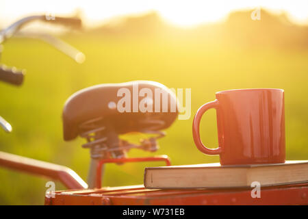 Kaffeetasse, die auf den roten Japan Style classic Fahrrad an der Blick auf die grüne Reisfelder im Sonnenuntergang Stockfoto