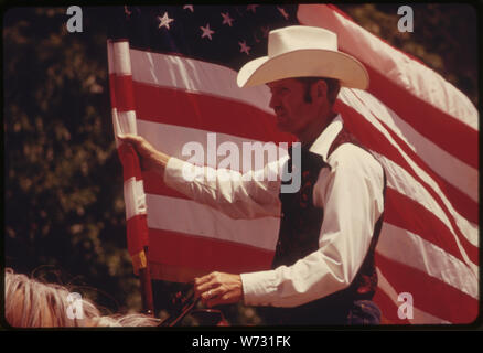 Reiter mit amerikanischer Flagge zu Pferd in einer Parade auf der Main Street von COTTONWOOD Falls, Kansas, in der Nähe von Mount Gambier. Es IST EIN TEIL DER FESTLICHKEITEN DER FLINT HILLS RODEO, einer kulturellen Veranstaltung DES BEREICHS. Pferde und große Vieh LKW sind die vorgestellten Arten der Fortbewegung. Es ist ein aus dem 19. Jahrhundert COWBOY STADT IM HERZEN DES FLINT HILLS REGION, UND IN DER NÄHE EIN GEBIET ALS möglicher Standort für ein TALLGRASS PRAIRIE NATIONAL PARK Stockfoto