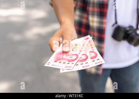 Hand von asiatischen Touristen geben Banknoten- und schwarzen Mappe, die er in Die touristische Attraktion gefunden. Wallet Konzept zu verlieren. Stockfoto