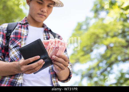 Asiatische Touristen zählen oder die Überprüfung der Banknoten in schwarz Brieftasche, die er in Die touristische Attraktion gefunden Stockfoto