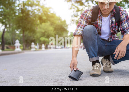 Asiatischer Mann picking schwarzen Mappe auf der Straße in touristische Attraktion. Wallet Konzept zu verlieren. Stockfoto