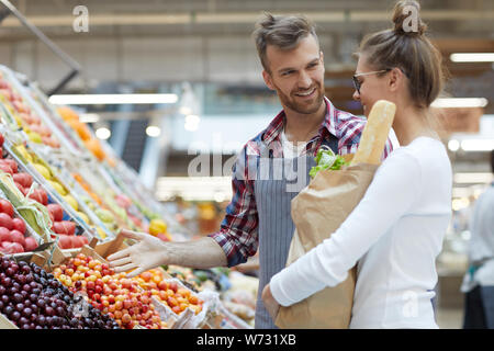 Taille bis Portrait von gutaussehenden jungen Mann helfen Kunden Obst im Supermarkt auswählen, kopieren Raum Stockfoto