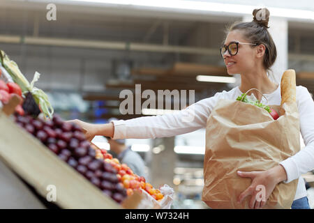 Seitenansicht Porträt des zeitgenössischen jungen Frau Wahl Obst an Farmers Market, Kopie Raum Stockfoto