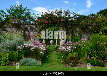 Torbogen und floralen Grenzen in einer typisch englischen Country Garden, Großbritannien Stockfoto