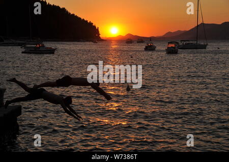 Zwei junge Männer ein Sonnenuntergang am Abend tauchen in Cavtat Hafen Kroatien Stockfoto