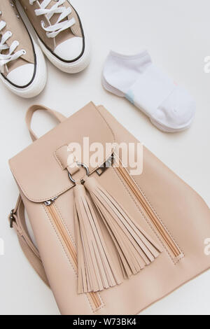 Beige Sneakers, Rucksack und rosa Kappe auf Pastell hellen Hintergrund. Platz für Text, Copyspace, flach. Stockfoto