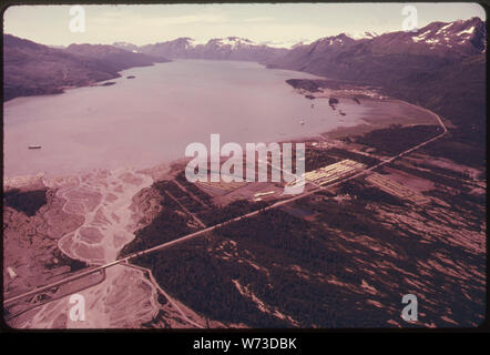 Blick nach Westen entlang PORT VALDEZ. TERMINAL WEBSITE SICHTBAR AM HANG IN DER MITTE LINKS ÜBER HALBINSEL (Jackson) und eine kleine Insel (Island). Stadt VALDEZ (1970 Bevölkerung 1974 Bevölkerung 1000; 2.000) ERSCHEINT MITTE RECHTS ETWA 418 MEILEN VON 48-Zoll Durchmesser ROHR IN YARDS IN DER UNTEREN MITTLEREN VORDERGRUND GESPEICHERT SIND. Die Richardson Highway BÖGEN ÜBER DEM UNTEREN VORDERGRUND zu schwingen, UM DEN NORDOSTEN VON PORT VALDEZ ZU ERREICHEN DIE NEUE STADT. 1,6 km 788-789 ALASKA PIPELINE ROUTE Stockfoto