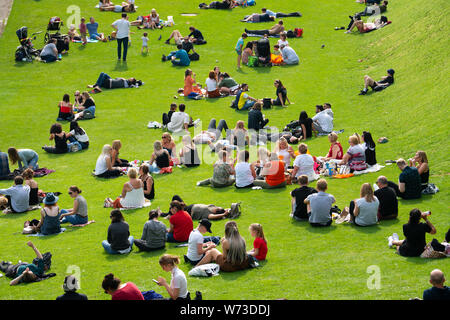 Leute sitzen auf Rasen an die Princes Street Gardens in warmen Sommerwetter in Edinburgh, Schottland, Großbritannien Stockfoto