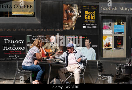 Paar draußen sitzen im Scottish Storytelling Centre während des Edinburgh Festivals auf der Royal Mile, Schottland, Großbritannien Stockfoto