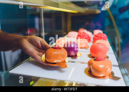 In der Nähe der Hände des Anbieters aus Kuchen aus der Showcase in Bäckerei. Stockfoto