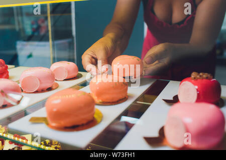 In der Nähe der Hände des Anbieters aus Kuchen aus der Showcase in Bäckerei. Stockfoto
