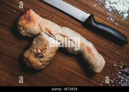 Zwei Stücke Brot, weißes Mehl, Wasser, Saatgut und ein Messer auf dem Tisch Stockfoto