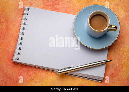 Leere Spirale Art Skizzenbuch mit einer Tasse Kaffee gegen strukturiertes Papier Stockfoto
