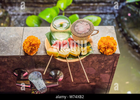 In Scheiben geschnittene Mango Melonen Papaya Melone Früchte auf nassen Grün Palm Leaf dekoriert Pink Frangipani Blume tropische Natur Hintergrund Stockfoto