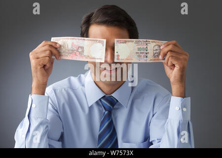 Geschäftsmann hält Banknoten vor seinen Augen Stockfoto