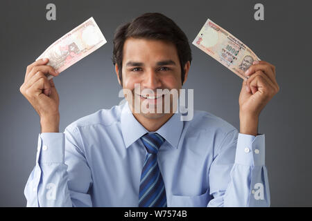 Geschäftsmann hält Banknoten lächelnd Stockfoto