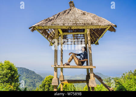 Junger Mann im traditionellen balinesischen Pavillon. Die Insel Bali Stockfoto