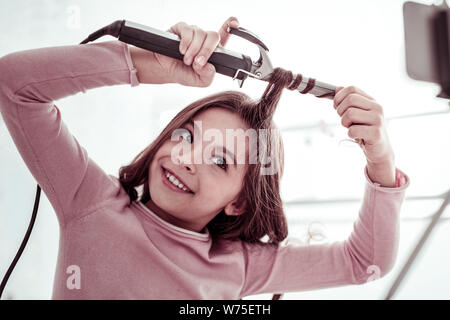 Schönes fröhliches Mädchen mit einem Lockenstab Stockfoto