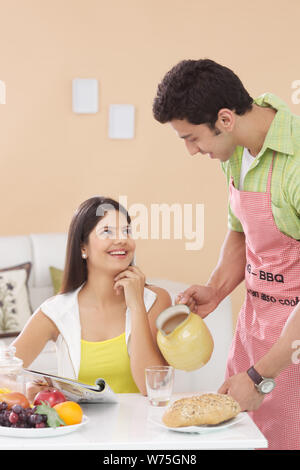 Indischer Mann Saft zu seiner Frau in Frühstück servieren Stockfoto