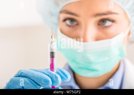Ärztin arbeiten mit Nadel und ampulle von Medizin. Ein Wissenschaftler in sterilen Kleidung ist ein Impfstoff, der Droge. Stockfoto