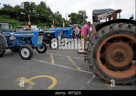 Menschen Prüfung Oldtimer Traktoren auf Anzeige an die 100 Royal Welsh Show 2019, Builth Wells Stockfoto