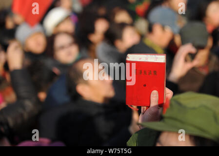 Das chinesische Volk eine "Ausgewählte Werke Mao Zedong' vor einer Statue der Chinesischen verstorbenen Vorsitzenden Mao Zedong seinen 124. Geburtstag zu Mark i Stockfoto