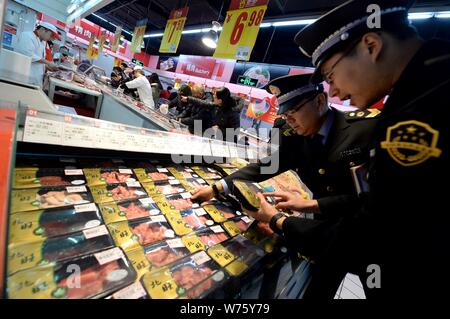 ------ Chinesische Polizeibeamte prüfen die Qualität von Fleisch in einem Supermarkt in Peking, China, 26. Dezember 2014. China's Qualität Regler s Stockfoto