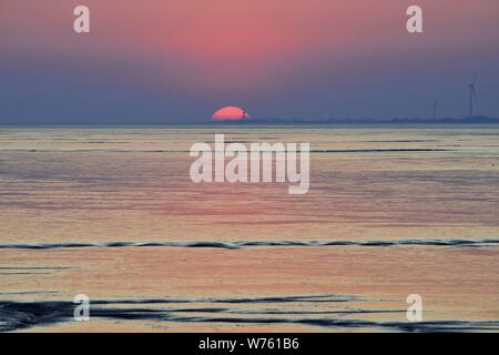 Fast Einstellung rote Sonne über dem Wattenmeer der Bucht Dollart bei Ebbe, 19. April 2019 | Verwendung weltweit Stockfoto