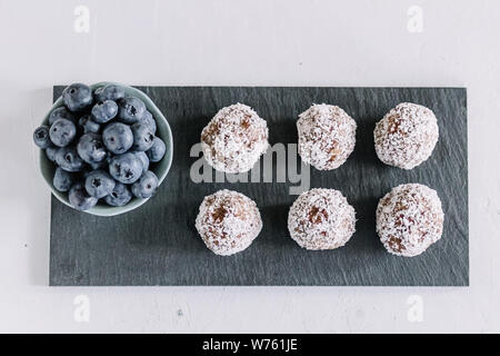 Hausgemachte Energie Kugeln mit Kokos und Heidelbeeren. Gesunde Lebensmittel für Kinder und vegan, Süßigkeiten ersetzen. Platz für Text. Stockfoto