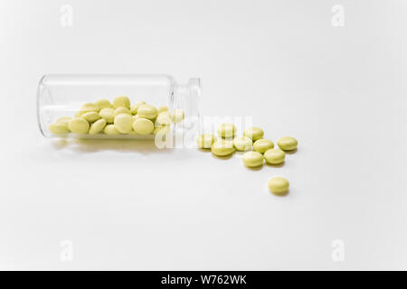 Gelbe Pillen auf weißem Hintergrund. Gelbe medizinische Pillen und Tabletten aus einer Droge Flasche. Kopieren Sie Platz. Stockfoto